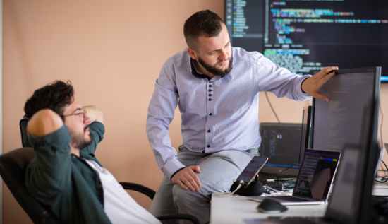 Embedded software developer working on microcontroller code with circuit board and laptop