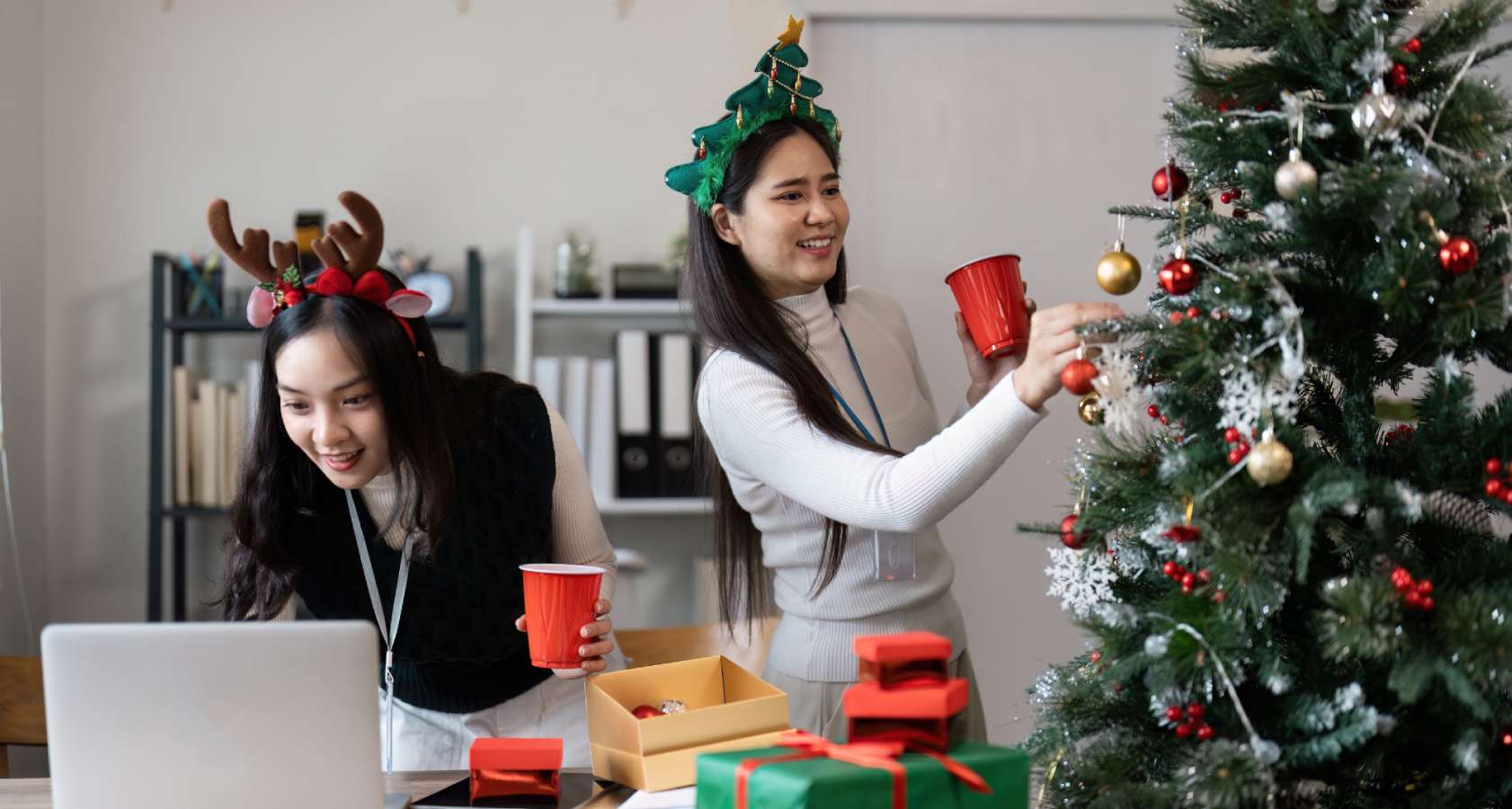 two women prepare Christmas tree at office